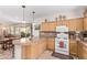 Functional kitchen area with breakfast bar, oak cabinets, white appliances, and tile flooring at 4203 E Narrowleaf Dr, Gilbert, AZ 85298