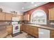 Well-lit kitchen with oak cabinetry, white appliances, and neutral countertops at 4203 E Narrowleaf Dr, Gilbert, AZ 85298