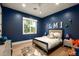 Bedroom with an accent wall in navy, neutral-toned decor, light hardwood floors, and a bright window at 6455 E Calle Del Media --, Scottsdale, AZ 85251