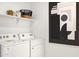 Functional laundry room with washer, dryer, floating shelf, and monochrome abstract wall art at 7436 W Buckhorn Trl, Peoria, AZ 85383