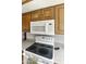 Functional kitchen featuring a white microwave and stove, complemented by wood cabinets and laminate countertops at 755 S Arrowwood Way, Mesa, AZ 85208