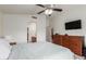 Bright bedroom featuring an arched doorway, ceiling fan, and a sleek wooden dresser with a mounted television at 927 E Baylor Ln, Gilbert, AZ 85296