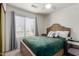 Cozy bedroom with a wooden bed frame, soft green bedding, and a nearby window for natural light at 927 E Baylor Ln, Gilbert, AZ 85296