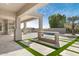 Expansive covered patio with travertine tile, integrated grill, grassy accents, and a clear view of the refreshing pool at 9826 N 131St St, Scottsdale, AZ 85259