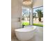 Modern bathroom featuring a sleek white tub, stylish fixtures, and serene views of the green outdoor landscape at 9826 N 131St St, Scottsdale, AZ 85259