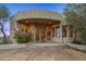 Stunning desert home showcases a grand entryway with artistic windows and lush foliage, adding elegance and privacy at 10325 E Celestial Dr, Scottsdale, AZ 85262