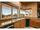 Kitchen sink area with stone counters, wood cabinets, and scenic views through windows at 10325 E Celestial Dr, Scottsdale, AZ 85262