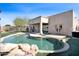 Inviting backyard pool area with a rock feature, artificial turf, and an outdoor kitchen with a built-in grill at 10816 W Palm Ln, Avondale, AZ 85392