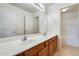 Bright bathroom features a dual sink vanity with wood cabinets and a large mirror reflecting the doorway and shower/tub at 13536 W Peck Dr, Litchfield Park, AZ 85340