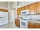 Bright kitchen with white appliances, neutral countertops, and wood cabinets at 13536 W Peck Dr, Litchfield Park, AZ 85340