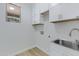 Laundry room boasts overhead cabinets, stainless steel sink, and a window for natural light at 19862 E Carriage Way, Queen Creek, AZ 85142