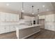 Bright kitchen with white cabinets, stainless hood, and large island with quartz countertops at 23805 N 163Rd Dr, Surprise, AZ 85387