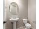 Elegant powder room with a pedestal sink and a round mirror at 23805 N 163Rd Dr, Surprise, AZ 85387