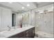 Luxurious bathroom featuring double sinks, a dark wood vanity, and a frameless glass walk-in shower at 3551 E Louise Dr, Phoenix, AZ 85050