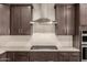 Updated kitchen featuring stainless steel range hood, tile backsplash, quartz countertops, and dark cabinets at 3551 E Louise Dr, Phoenix, AZ 85050