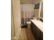 Bathroom showcasing a shower with a patterned curtain, tiled floors, and dark wood cabinetry at 42920 N Raleigh Ct, Anthem, AZ 85086