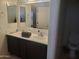 Bright bathroom featuring double sinks with dark wood cabinetry and a large mirror at 42920 N Raleigh Ct, Anthem, AZ 85086