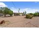 Large gravel backyard adorned with trees, lush landscaping, and desert plants, creates a tranquil outdoor retreat at 5463 E Albany St, Mesa, AZ 85205