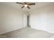 This bedroom includes neutral carpet, a ceiling fan, and a closet at 562 N 104Th St, Mesa, AZ 85207