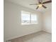 This bedroom includes neutral carpet, a ceiling fan, and a window overlooking the street at 562 N 104Th St, Mesa, AZ 85207