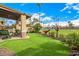 Serene backyard featuring a covered patio, lush green lawn, desert landscaping, and views of the golf course at 6202 E Mckellips Rd # 46, Mesa, AZ 85215