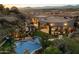 Desert home's outdoor living space with pool, covered patio, lush landscaping, and breathtaking mountain views at 10471 E White Feather Ln, Scottsdale, AZ 85262