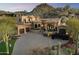 Luxurious Tuscan-style home with a circular driveway, grand staircase, and desert landscaping against a mountain backdrop at 10471 E White Feather Ln, Scottsdale, AZ 85262