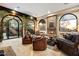 Inviting living room with a stone fireplace, leather seating, and large windows showcasing picturesque desert views at 10471 E White Feather Ln, Scottsdale, AZ 85262