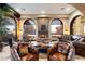 Cozy living room with a stone fireplace, arched windows, and leather seating offers a warm and inviting atmosphere at 10471 E White Feather Ln, Scottsdale, AZ 85262