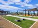 Community common area with cornhole, turf, playground, and seating under shade canopies at 16076 W El Cortez Pl, Surprise, AZ 85387