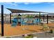 Community playground with a slide and various play structures, covered by a large shade at 16076 W El Cortez Pl, Surprise, AZ 85387