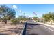 Community entrance featuring flags, mature trees and desert landscaping at 1631 N Lynch --, Mesa, AZ 85207