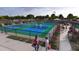 A view of people enjoying the outdoor pickleball courts featuring shaded seating surrounded by lush landscaping and greenery at 24886 N 167Th Dr, Surprise, AZ 85387