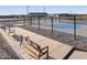 Outdoor pickleball courts with blue playing surfaces, surrounded by black fencing, concrete walkways, and comfortable benches at 37083 W Prado St, Maricopa, AZ 85138