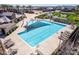 Aerial view of a large community pool with a sunshade, lounge seating, and nearby playground in a residential area at 4156 E Bernice St, Gilbert, AZ 85295