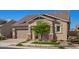 Inviting home showcasing a two-car garage, stone detailing, complemented by a lush green lawn and blooming flowers at 4156 E Bernice St, Gilbert, AZ 85295