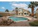 Beautiful backyard featuring a sparkling pool, palm trees, and desert landscaping at 4613 E Douglas Ave, Gilbert, AZ 85234