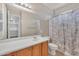 A bathroom with a vanity sink and mirror, plus a shower/tub with a leafy patterned curtain at 6409 S 49Th Dr, Laveen, AZ 85339