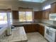 Kitchen showcasing wood cabinets, beige tiled counter tops, and natural light at 7636 E Coronado Rd, Mesa, AZ 85207