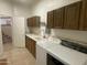 Well-lit laundry room with tile flooring, washer, dryer, cabinets, and sink adjacent to an interior staircase at 7636 E Coronado Rd, Mesa, AZ 85207