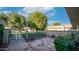 Cozy tiled patio with brick accents, wrought iron gate, lush trees, and charming landscaping at 9523 W Sandstone Dr, Sun City, AZ 85351