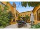 Charming outdoor courtyard with stone patio, fireplace, dining set, and lush greenery at 10040 E Happy Valley Rd # 269, Scottsdale, AZ 85255