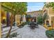 Serene courtyard featuring stone patio, wrought iron furniture, mature trees, and outdoor lighting at 10040 E Happy Valley Rd # 269, Scottsdale, AZ 85255