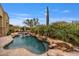 Lush backyard pool featuring rock accents, a waterfall, and mature desert landscaping under a blue sky at 10040 E Happy Valley Rd # 269, Scottsdale, AZ 85255