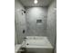 Remodeled bathroom with white marble tile surround, shower, and alcove storage at 10463 W Medlock Dr, Glendale, AZ 85307