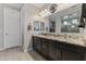 A main bathroom boasts double sinks with granite counters, dark cabinets, and a large mirror for added appeal at 12531 W Tuckey Ln, Glendale, AZ 85307