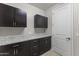 Spacious laundry room featuring dark cabinets, granite countertops, and a convenient door at 12531 W Tuckey Ln, Glendale, AZ 85307
