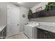Well-equipped laundry room with modern washer and dryer, dark cabinets, and elegant granite countertops at 12531 W Tuckey Ln, Glendale, AZ 85307