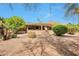 View of the back exterior featuring a large covered patio, desert landscaping, and blue sky at 16131 W Indianola Ave, Goodyear, AZ 85395