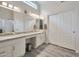 Bright bathroom boasts a double sink vanity with a granite countertop, white cabinets and new flooring at 16131 W Indianola Ave, Goodyear, AZ 85395
